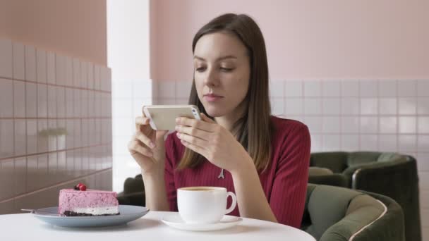 Mooie brunette meisje foto van taart doen zittend in een café. Probleem vandaag, sociaal netwerk. 60 fps — Stockvideo