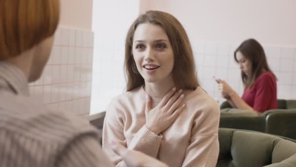 Tres chicas caucásicas jóvenes sentadas en un café y sonriendo, hablando, dialogando, con emoción de sorpresa, con concepto de chismes. Fondo 60 fps — Vídeos de Stock