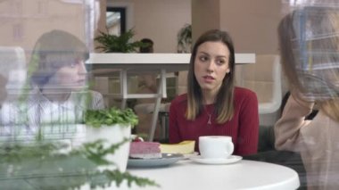 Üç genç kız, kafeler, arkadaşlar, şirket, dedikodu, diyalog, tartışma oturuyor. Kafe kavramı kız. çay, kek yeme içme. 60 fps