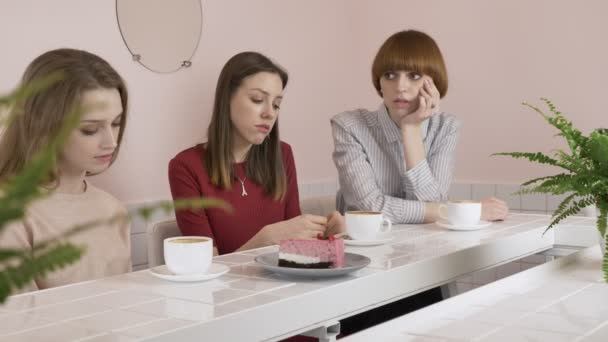 Три кавказькі дівчат сидячи в кафе, пити каву, їдять торт, сумно, жести, своїми руками, плітки старих подруг в кафе концепцію. 60 кадрів в секунду — стокове відео