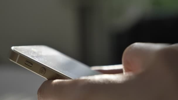 Mens mãos mensagens de texto em um smartphone branco, digitação, luz solar na tela, reflexão, conceito de mensagem. Destaque ensolarado, feixe, raio. Fechar 60 fps — Vídeo de Stock