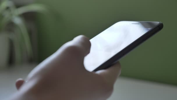 Vrouwelijke handen met grote zwarte smartphone, een zonnige tabel op de achtergrond, close-up 60 fps — Stockvideo