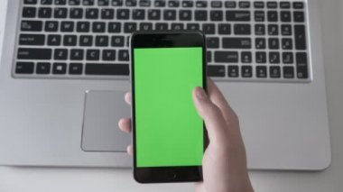 Erkek daha büyük bir siyah smartphone, laptpo içinde belgili tanımlık geçmiş kaydırma eller. Yeşil ekran, chromakey kavramı, laptop içinde belgili tanımlık geçmiş. 60 fps vurdu top