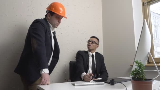 Dos jóvenes empresarios, arquitecto, discuten el proyecto y miran al monitor en la oficina. Constructores, ingenieros, concepto. 60 fps — Vídeo de stock