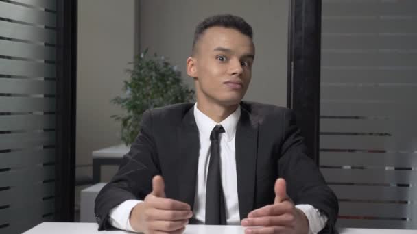 Der junge erfolgreiche afrikanische Geschäftsmann im Anzug zeigt sich überrascht, schüttelt den Kopf und sitzt im Büro. 60 fps — Stockvideo