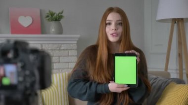 Kızıl saçlı kız blogger, gülümseyen, kameraya konuşurken, bir yeni satın alma, tablet, uygulama, yeşil ekran, chroma key, ev konfor arka planda gösterilen. 60 fps