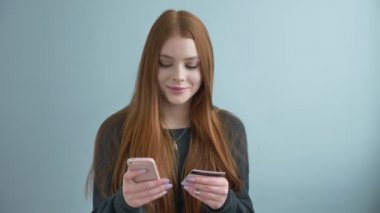 Genç güzel kızıl saçlı kız bir satın alma online, yaşam tarzı, bu evde kredi kartı ile alışveriş online smartphone kullanarak online bankacılık yapar. teknoloji ve internet kavramı 60 fps