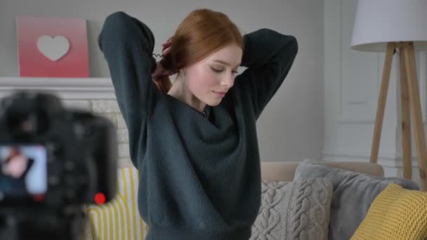 Young red-haired girl blogger, smiling, talking at the camera, Makes herself a hairstyle, tress, home comfort in the background. 60 fps — Stock Video
