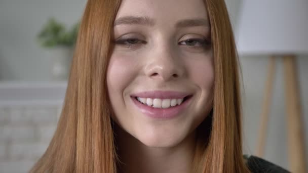 Молодая рыжеволосая девушка блоггер, портрет, смотрит на камеру, серьезное лицо, улыбается, красивые глаза, выглядит 60 кадров в секунду — стоковое видео