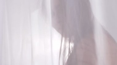 Genç Beyaz sarışın kız dokunuşlar perde, tül ve bakar kamera, portre, iğfal, arka planda, siluet kavramı, güneş ışığı, seksi iç çamaşırı yakın kadar 60 fps