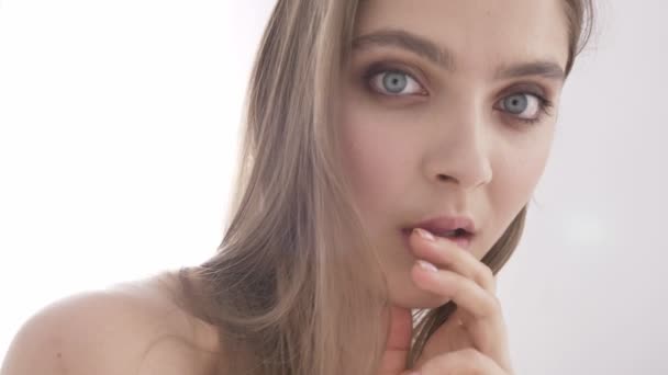 Porträt einer jungen kaukasischen sexy Mädchen berühren Lippen, lächelnd, Versuchung, weißes Licht auf dem Hintergrund 60 fps — Stockvideo