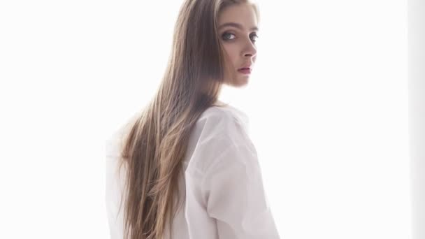 Portrait of a beautiful young Caucasian girl in a white shirt, temptation, sexy, white sunlight in the background. 60 fps — Stock Video