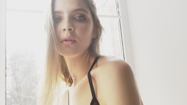 Όμορφη σέξι Καυκάσιος κοπέλα με άσπρο πουκάμισο βλέπουν πορτρέτο, πειρασμός, κάμερα, σέξι, λευκό φως του ήλιου στο παρασκήνιο. 60 fps — Αρχείο Βίντεο