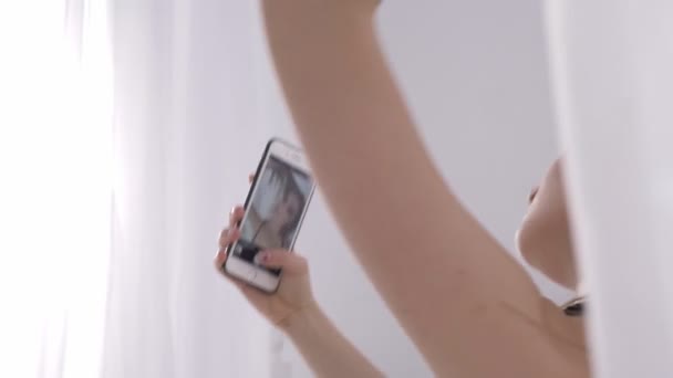 Молодая кавказская девушка в сексуальном белье стоя и делая селфи, портрет, искушение, сексуальные ноги, солнечный свет на заднем плане, концепция, 60 кадров в секунду — стоковое видео