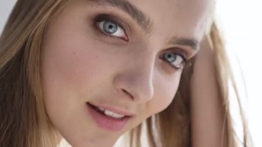 Genç güzel beyaz kadın arıyor, kamera, gülümseyen, portre, gün ışığı, pencere, yakınındaki perde, 50 fps kadar yakın