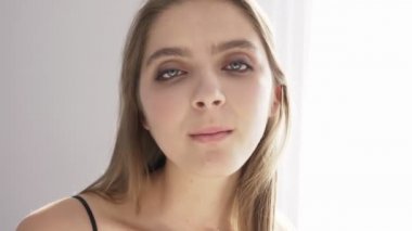 Genç güzel beyaz kadın arıyor, kamera, gösteren dil, yetişkin çocuk, portre, güneş ışığı, pencere, yakındaki 50 fps perde