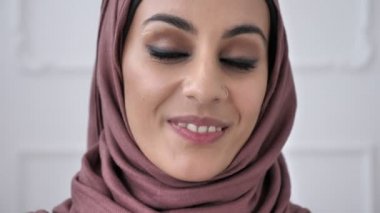 Piercing ile genç güzel Hintli kız gülümseyerek ve kameraya bakarak pembe hijab burnuna içinde. Portre, ağaç, beyaz arka plan, yakın 60 fps yukarı