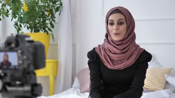 Gülümseyen, genç güzel Hint kızı kameraya konuşurken hijab blogger diyor gösteren işareti kalp, beyaz oda, arka plan ev rahatlığında gibi repost, kanala abone olun. 50 fps — Stok video