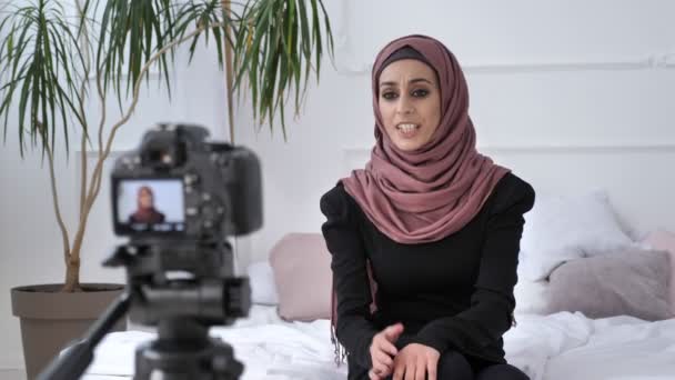 Ung vacker indisk flicka i hijab blogger talar på kamera, räkningarna, upprörda, gestikulerande, vita rummet, hem komfort i bakgrunden. Stäng upp 50 fps — Stockvideo