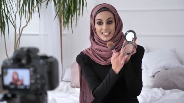 Menina indiana bonita nova no blogueiro hijab falando na câmera, sorrindo, falando para a câmera, mostrando uma nova compra, pincel de maquiagem, Palete de sombra, conforto em casa no fundo. 60 fps — Vídeo de Stock
