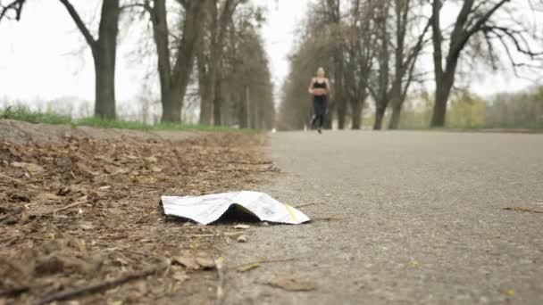 年轻漂亮的女孩穿着黑色运动服在路上奔跑在一个盛开的公园, 底部视图, plogging 概念, 50 fps — 图库视频影像