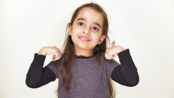 Pequeña linda niña está sonriendo y mostrando como signo, aprobando, ok, agradable, retrato, fondo blanco 50 fps — Vídeo de stock