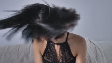 Genç Beyaz esmer kız kanepede oturan, gülüyor, onun baş 50 fps sallayarak siyah iç çamaşırı