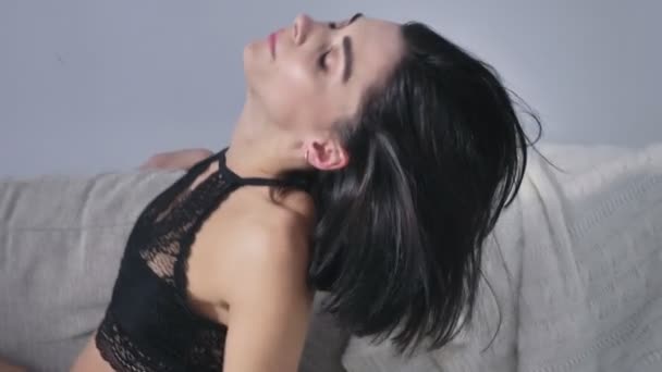 Tineri caucazian bruneta fata în lenjerie de corp negru se ridică erotic de pe canapea 50 fps — Videoclip de stoc