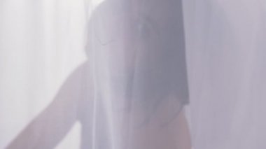 Seksi bir pencere, gün ışığı, bir kişi bir perdenin arkasında close-up yakınındaki bir tül arkasındaki bir kadın silüeti 50 fps