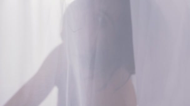 Сексуальный силуэт женщины за тюлем, рядом с окном, дневной свет, крупный план человека за занавесом 50 кадров в секунду — стоковое видео