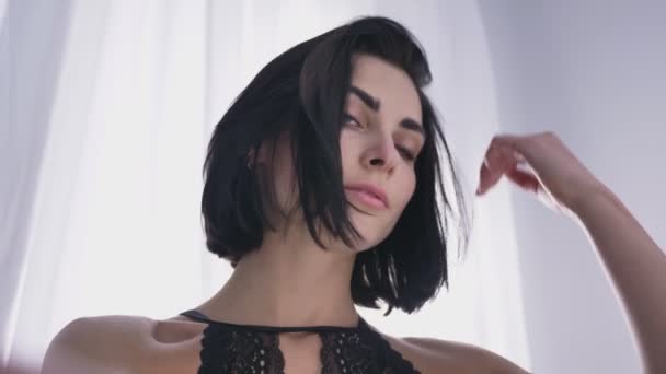 Portrét mladé sexy kavkazských bruneta v černém prádle, při pohledu na fotoaparát, dotýká jejích vlasů, blikající 50 fps
