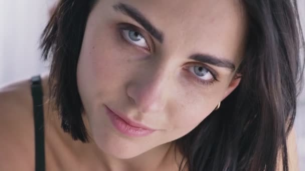 Portret młodej dziewczyny Brunetka kaukaski, patrząc na kamery, niebieskie oczy, uśmiech, dotykając karku. — Wideo stockowe