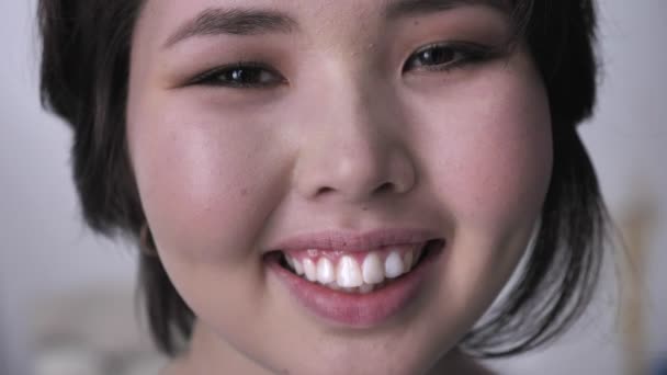 Portrét mladé šťastný asijské bruneta dívky, při pohledu na fotoaparát, usmívající se tvář. 50 fps