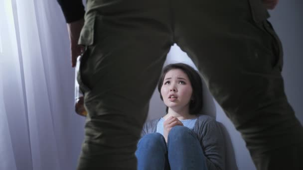 Sorgliga asiatisk kvinna sitter på golvet, berusad man förbereder att slå sin fru, en konflikt i familjen, våld 50 fps — Stockvideo