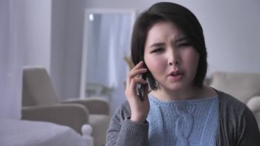 Genç üzücü Asyalı kız agresif kullanma smartphone, portre, sarhoş koca telefonda konuşuyor içinde 50 fps arka plan