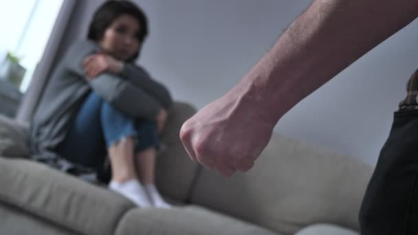 Begreppet våld i familjen, manlig näve rädd asiatisk kvinna sitter i soffan i bakgrunden 50 fps — Stockvideo