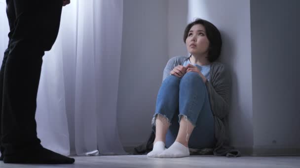 Sorgliga asiatisk kvinna sitter på golvet, arg man hotar, konflikter i familjen, våld 50 fps — Stockvideo