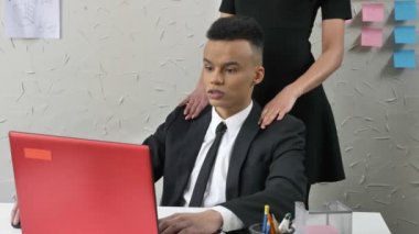 Genç patron genç bir Afrika karışık çalışanı ile flört ediyor, nazikçe omuzlarına masaj, taciz kavramı, ofis iş dokunuşlar yakın kadar 50 kare/sn