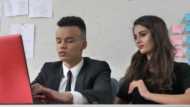 Junge Chefin sitzt neben ihrem afrikanischen Mitarbeiter, umarmt ihn sanft, flirtet, Belästigungskonzept 50 fps — Stockvideo