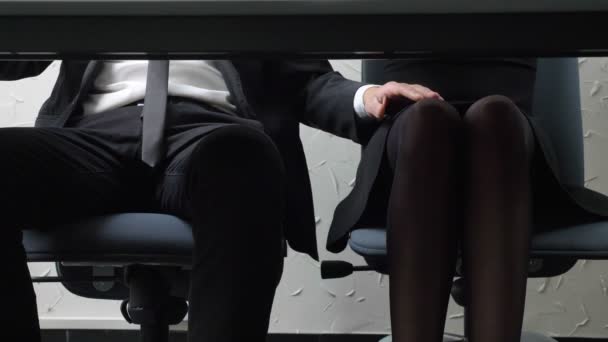 Disparando debajo de la mesa, un joven con traje, el jefe toca la pierna de sus empleados, ella enfrente, coquetea, concepto de acoso 50 fps — Vídeo de stock