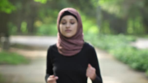 Portrait of a young girl running in a frame in hijab, on nature, in a park in the background. 50 fps — Stock Video