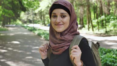 Hijab ayakta kavramı seyahat bir sırt çantası ile parkta genç gülümseyen kız portresi 50 fps