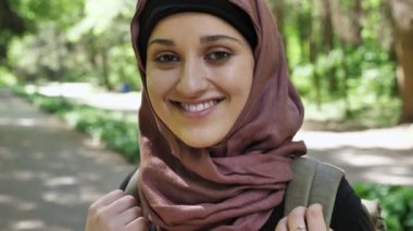 Hijab ayakta kavramı seyahat bir sırt çantası ile ormandaki bir genç gülümseyen kız portresi 50 fps