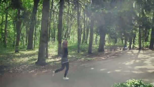Jeune fille athlétique en hijab courir, faire du jogging dans un parc vert, vue latérale 50 fps 