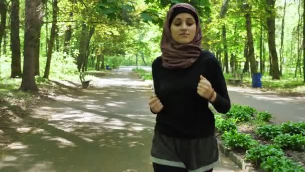 운동 소녀 hijab 실행, 녹색 공원에 조깅에, 전면 보기 50 fps — 비디오