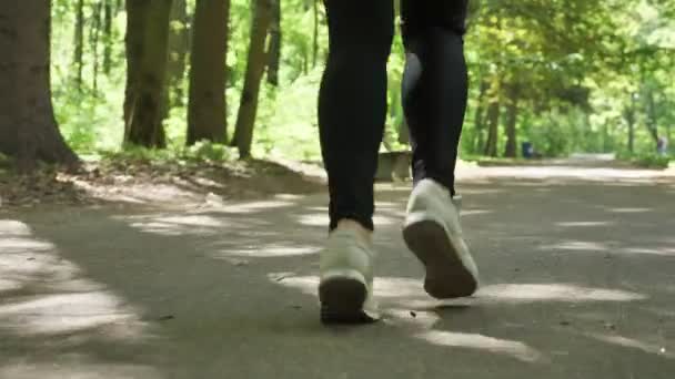 Close-up van vrouwelijke benen in loopschoenen joggen in park 50 fps — Stockvideo