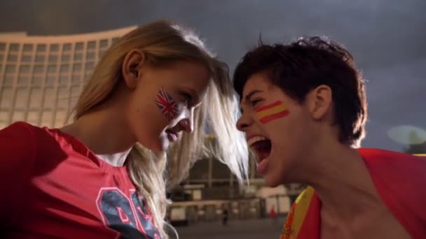 Två unga flickor, fotboll fläktar, England mot Spanien, konfrontation, skrikande, stadium i bakgrunden 50 fps — Stockvideo