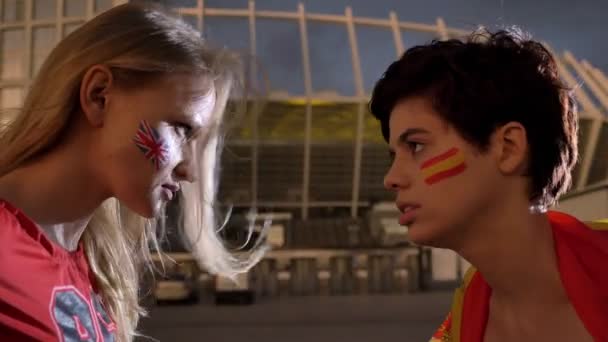 Deux jeunes filles, fans de football, l'Angleterre contre l'Espagne, confrontation, vent, stade en arrière-plan 50 fps — Video