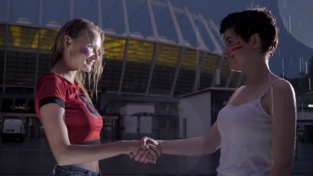 Liga Mistrzów, dwie młode dziewczyny fanów piłki nożnej w deszczu są drżenie rąk, pojęcie przyjaźni 60 fps — Wideo stockowe