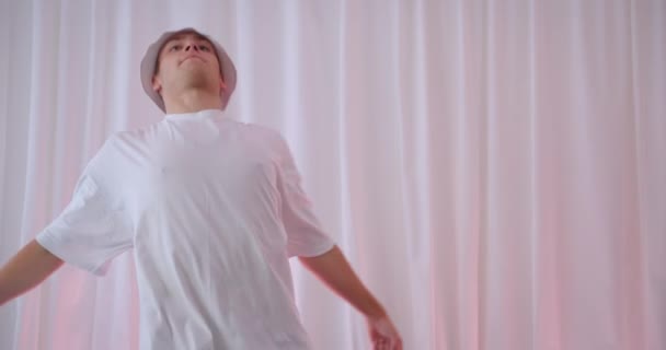 Nahaufnahme Porträt eines jungen qualifizierten kaukasischen Mannes mit Eimerhut, der drinnen in einer Wohnung tanzt — Stockvideo